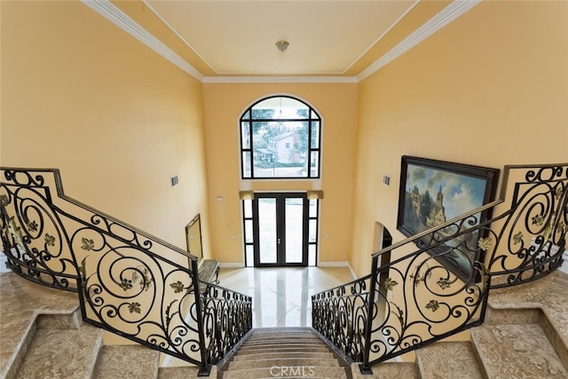 entryway with a high ceiling, crown molding, and french doors