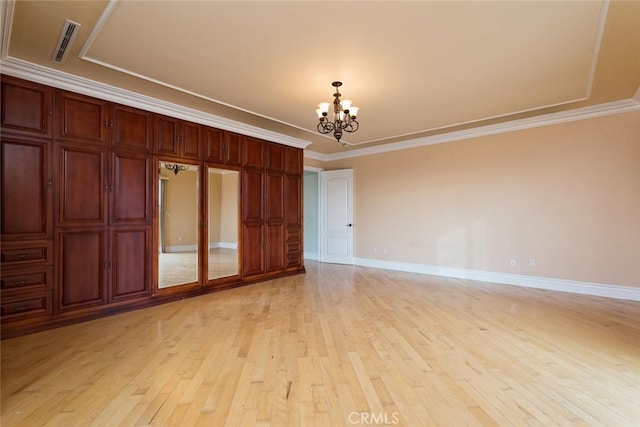 empty room with light wood-type flooring, an inviting chandelier, and ornamental molding