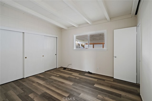 unfurnished bedroom with vaulted ceiling with beams, a closet, and dark hardwood / wood-style floors