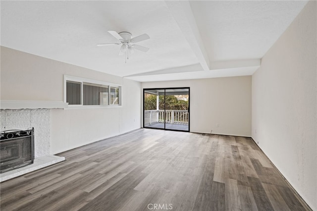 unfurnished living room featuring ceiling fan, a brick fireplace, beamed ceiling, and hardwood / wood-style floors