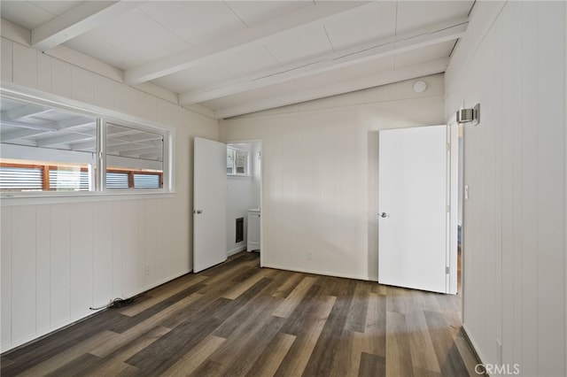 empty room featuring dark hardwood / wood-style floors, wooden walls, and beamed ceiling