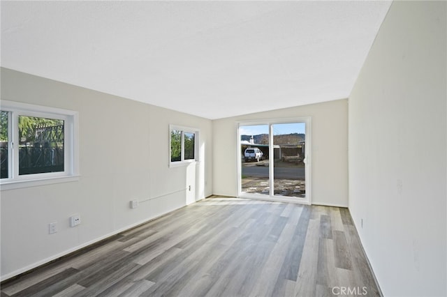 spare room with wood-type flooring and vaulted ceiling