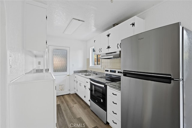 kitchen featuring white cabinets, appliances with stainless steel finishes, tasteful backsplash, sink, and light hardwood / wood-style flooring