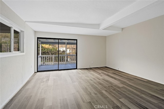 empty room featuring beam ceiling and light hardwood / wood-style flooring