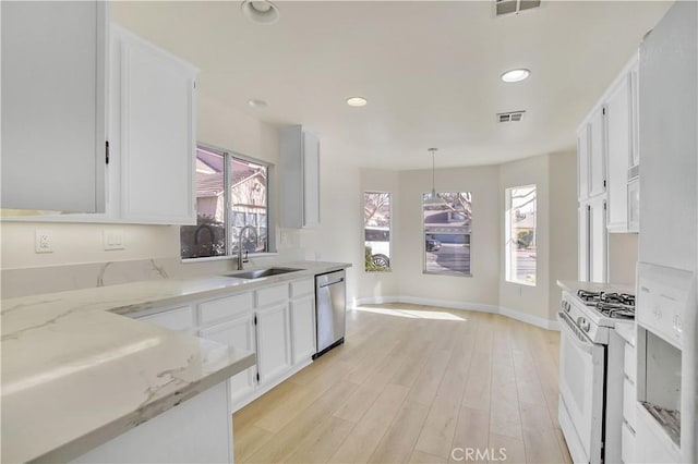 kitchen with decorative light fixtures, white gas range oven, stainless steel dishwasher, sink, and white cabinetry