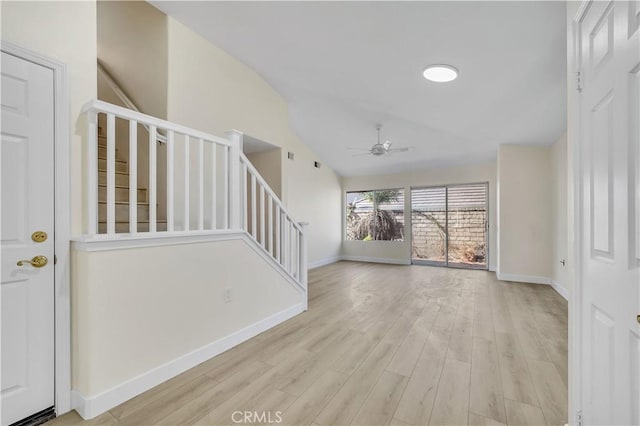 unfurnished living room with ceiling fan, vaulted ceiling, and light wood-type flooring