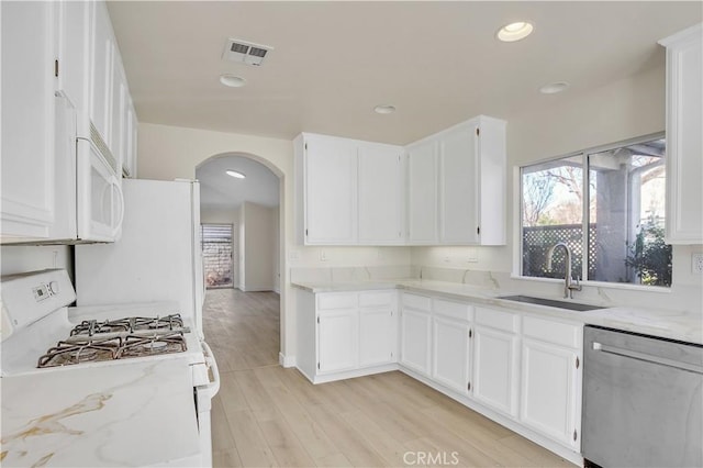 kitchen featuring light stone countertops, sink, white appliances, and white cabinetry