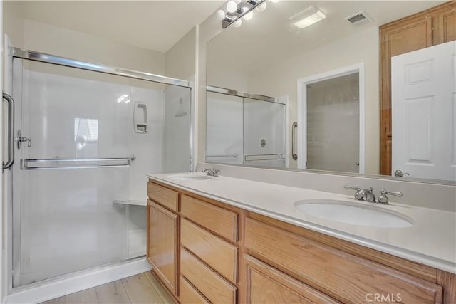 bathroom with a shower with shower door, wood-type flooring, and vanity