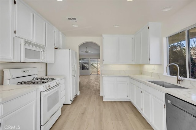 kitchen featuring sink, white appliances, and white cabinetry