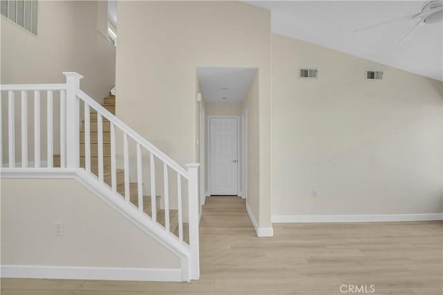 stairway with ceiling fan, hardwood / wood-style floors, and lofted ceiling