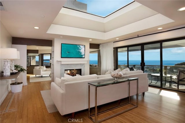 living room with a high ceiling, a premium fireplace, and light hardwood / wood-style flooring