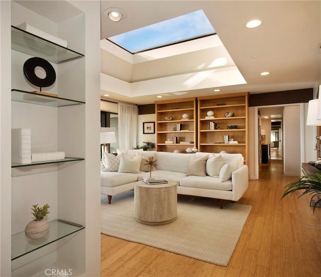 living room with a high ceiling, hardwood / wood-style floors, and a skylight