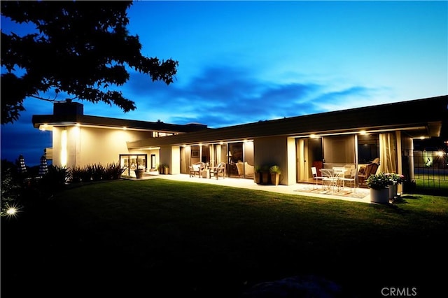 back house at dusk featuring a yard