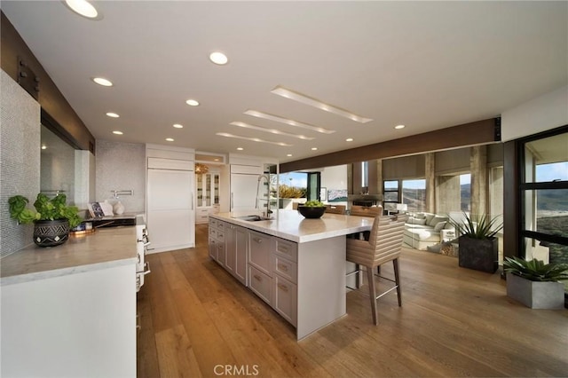 kitchen with gray cabinetry, hardwood / wood-style floors, a kitchen breakfast bar, and a spacious island