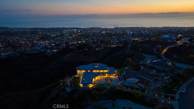 aerial view at dusk featuring a water view