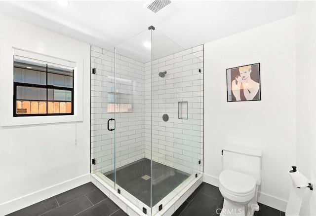 bathroom featuring toilet, a shower with door, and tile patterned flooring