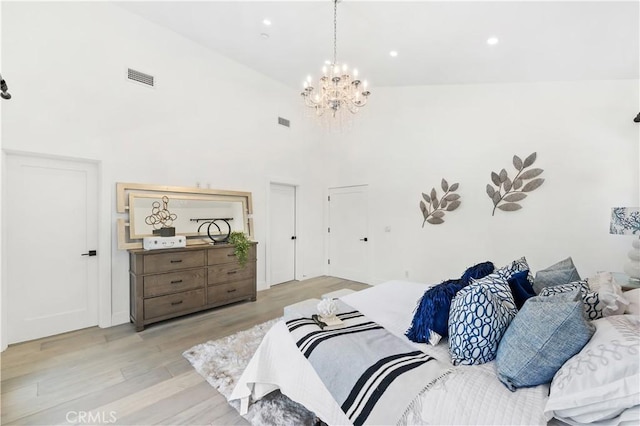 bedroom with high vaulted ceiling, a notable chandelier, and light hardwood / wood-style floors