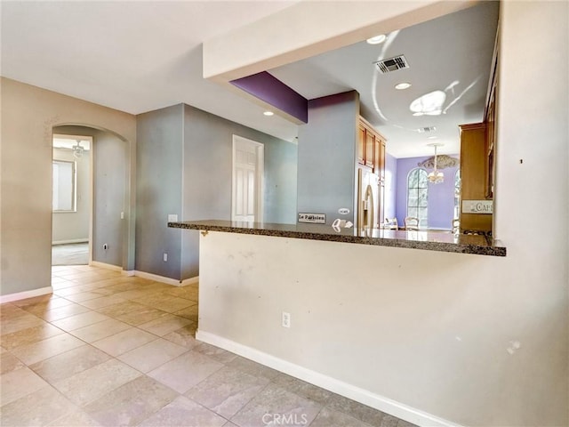 kitchen featuring pendant lighting, stainless steel fridge with ice dispenser, kitchen peninsula, and a chandelier