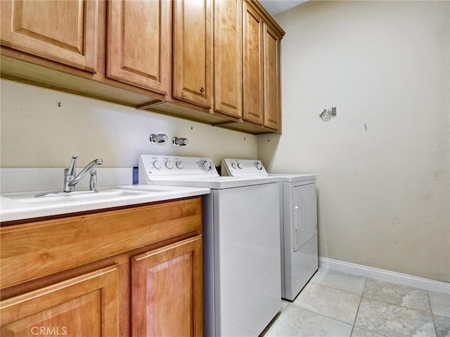 washroom with cabinets, light tile patterned floors, washer and clothes dryer, and sink