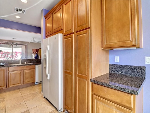 kitchen with white appliances, dark stone counters, sink, ceiling fan, and light tile patterned floors