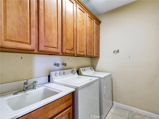 clothes washing area with cabinets, light tile patterned floors, washing machine and clothes dryer, and sink