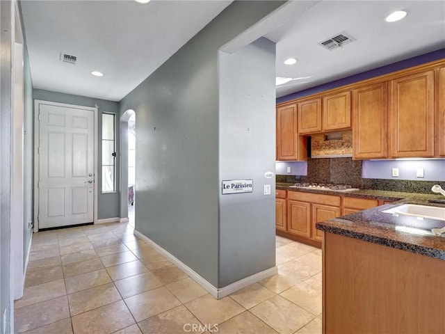 kitchen with light tile patterned floors, backsplash, gas cooktop, and sink