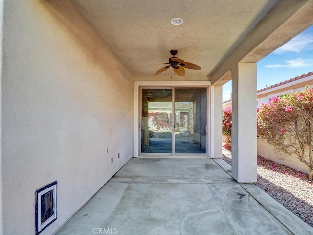 view of exterior entry featuring ceiling fan and a patio area