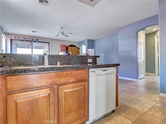 kitchen with dishwasher, dark stone countertops, sink, ceiling fan, and light tile patterned floors