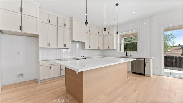 kitchen with light stone countertops, white cabinets, dishwasher, a kitchen island, and hanging light fixtures