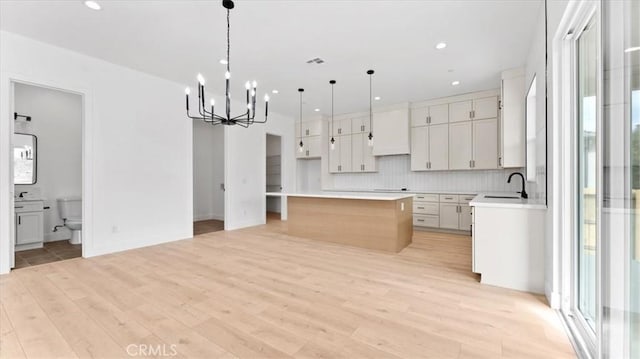 kitchen with backsplash, a notable chandelier, pendant lighting, a center island, and white cabinets