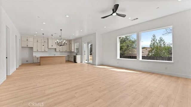 unfurnished living room featuring light hardwood / wood-style floors and ceiling fan with notable chandelier