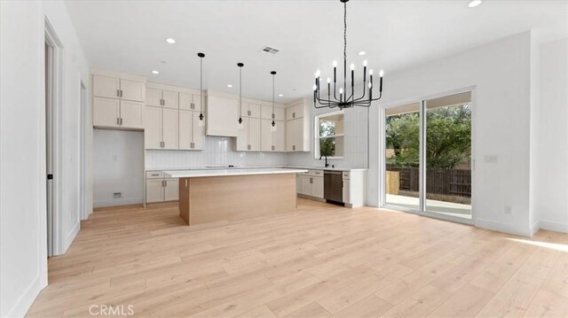 kitchen with a center island, decorative light fixtures, white cabinetry, light wood-type flooring, and stainless steel dishwasher