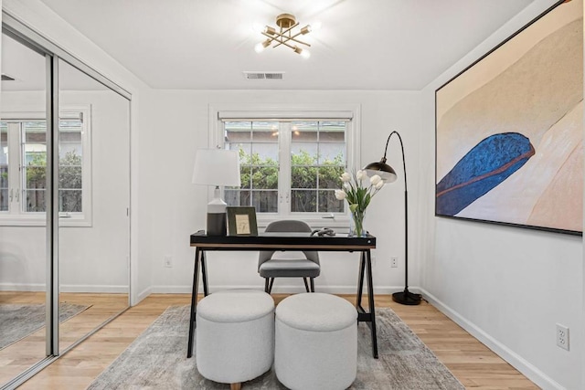 office space with light hardwood / wood-style floors and an inviting chandelier