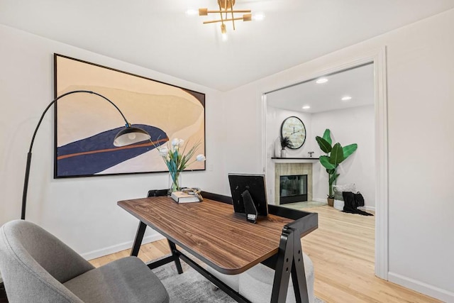 office space featuring a fireplace, hardwood / wood-style floors, and an inviting chandelier