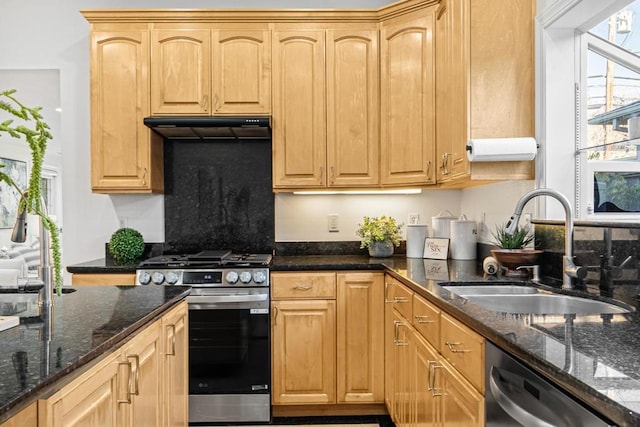 kitchen featuring light brown cabinetry, sink, dark stone counters, and appliances with stainless steel finishes