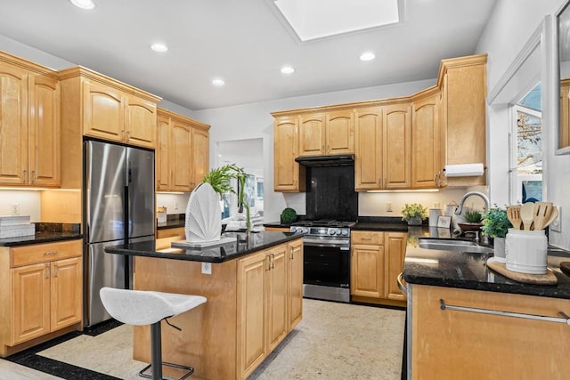 kitchen with a skylight, a center island, sink, stainless steel appliances, and dark stone counters