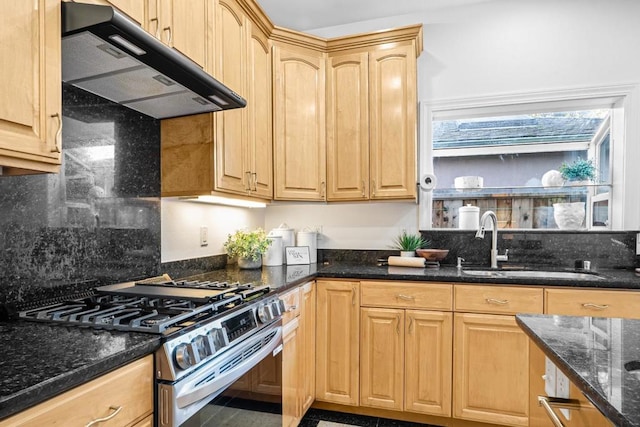 kitchen with light brown cabinets, stainless steel gas stove, dark stone counters, and sink