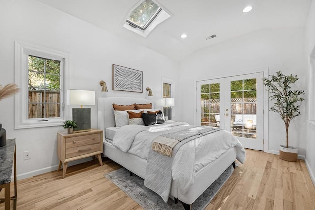 bedroom featuring access to exterior, vaulted ceiling with skylight, multiple windows, and french doors