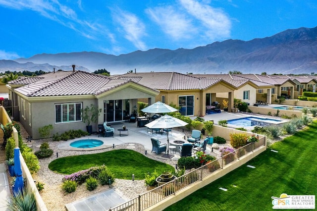 back of house featuring a lawn, a pool with hot tub, a patio area, and a mountain view