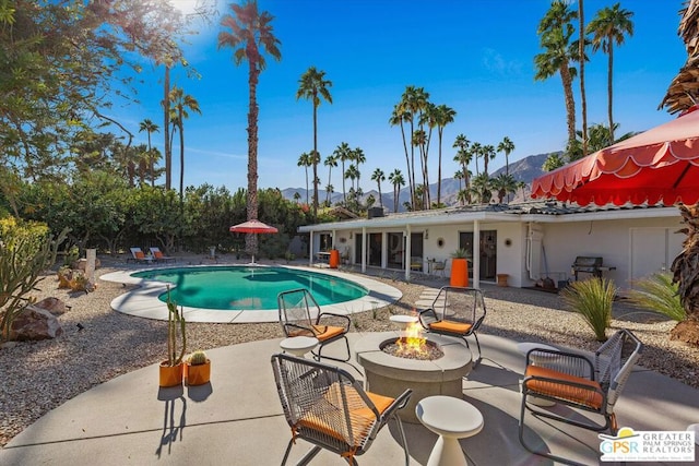 view of pool with a mountain view, a patio, and a fire pit