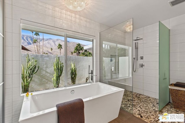 bathroom featuring a chandelier, tile patterned flooring, a mountain view, tile walls, and separate shower and tub