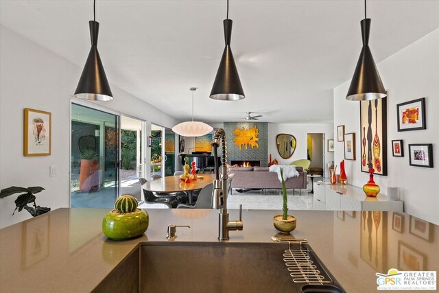 kitchen featuring ceiling fan, a fireplace, sink, and hanging light fixtures