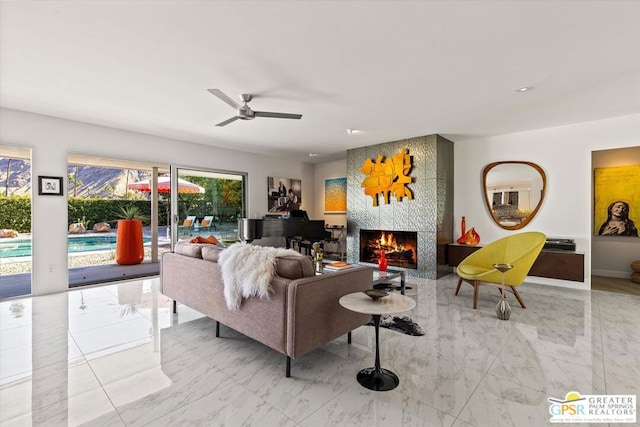 living room featuring ceiling fan and a tiled fireplace