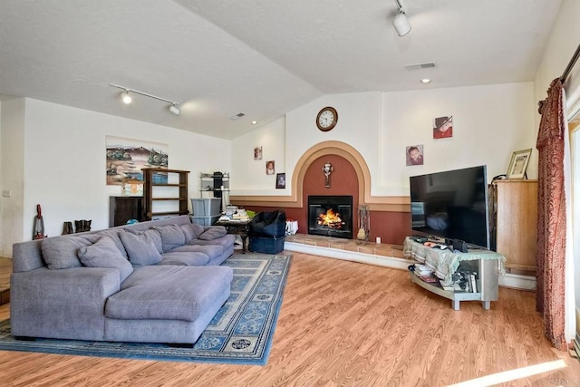 living room with vaulted ceiling, track lighting, and light hardwood / wood-style flooring