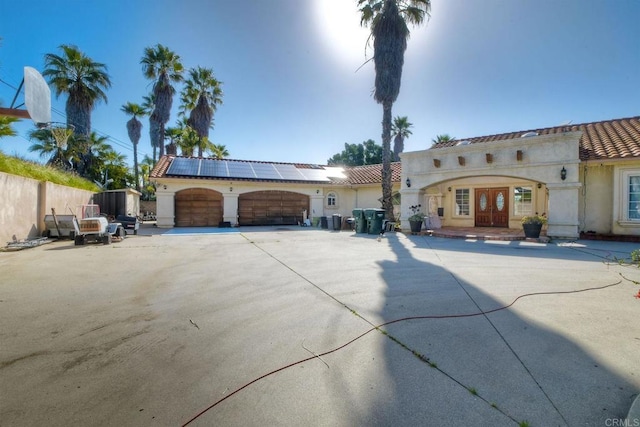 view of front facade featuring french doors, solar panels, and a garage