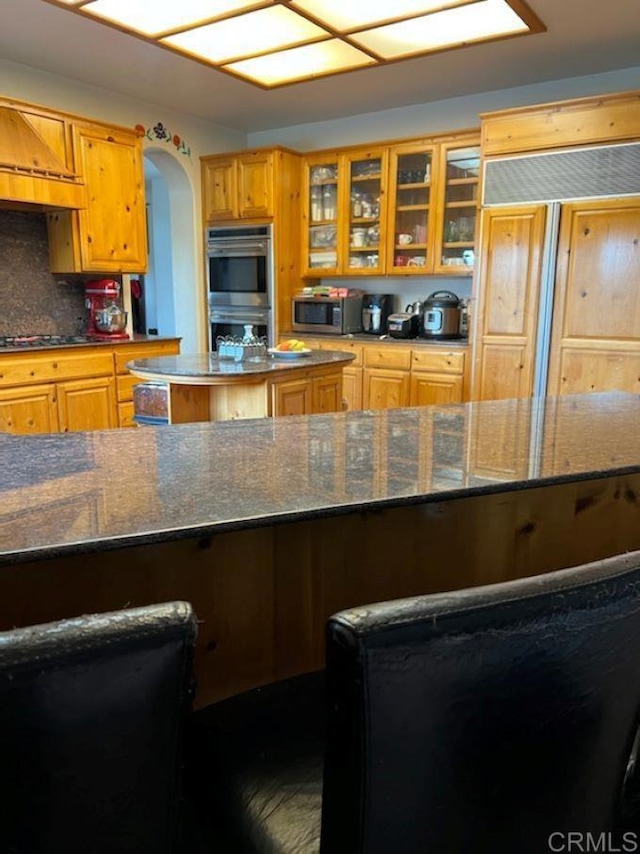 kitchen featuring tasteful backsplash, dark stone countertops, stainless steel appliances, and a center island