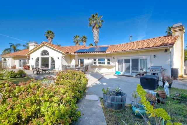 rear view of property featuring solar panels and a patio