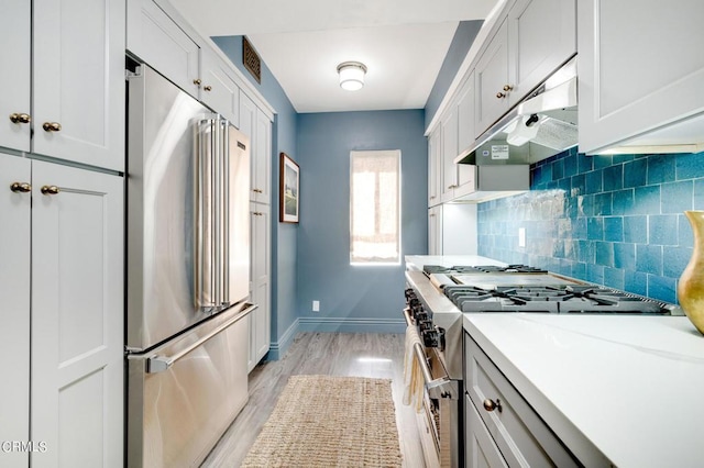 kitchen with light wood-type flooring, decorative backsplash, high end appliances, and white cabinetry