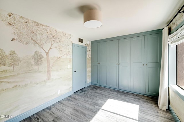 unfurnished bedroom featuring light wood-type flooring and a closet