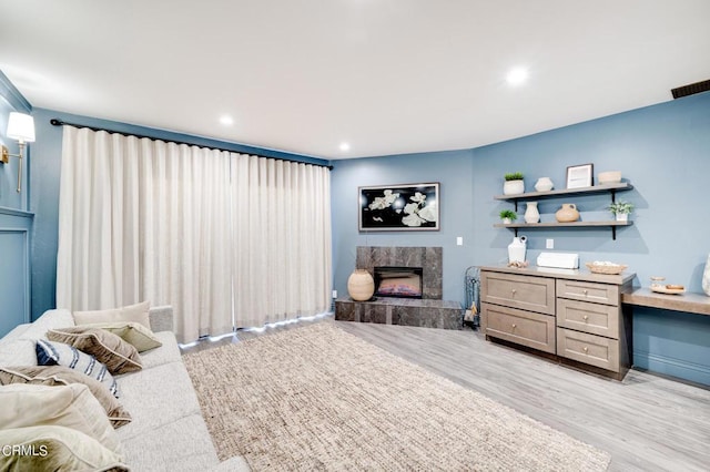 bedroom featuring a high end fireplace and light hardwood / wood-style floors